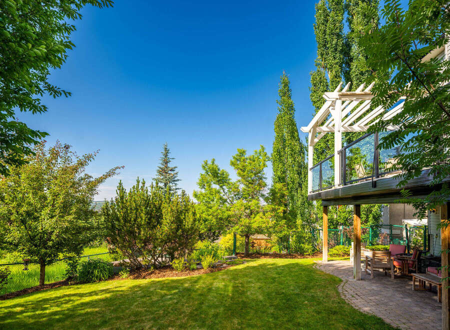 Enjoy outdoor living in this beautifully landscaped backyard featuring a spacious deck with a pergola, perfect for entertaining.
