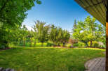 Enjoy the lush green lawn and mature trees in this beautiful backyard, perfect for outdoor entertaining and relaxation.