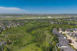 Discover this stunning aerial view showcasing a sprawling suburban landscape with modern homes nestled amidst lush greenery and rolling hills.