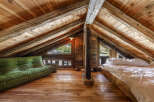 Experience rustic charm in this unique attic loft bedroom, featuring exposed wooden beams and a cozy green sofa.