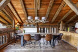 Experience rustic charm in this mountain chalet dining area, featuring a large wooden table with comfortable seating and a unique driftwood chandelier.