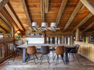Experience rustic charm in this mountain chalet dining area, featuring a large wooden table with comfortable seating and a unique driftwood chandelier.