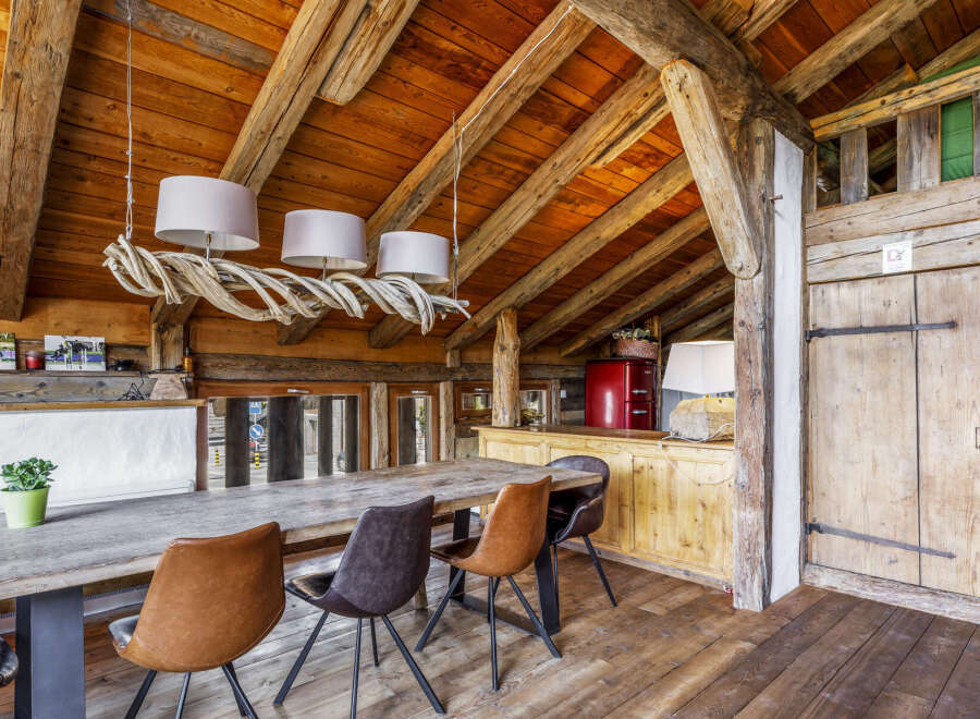 Experience rustic charm in this dining area featuring a large wooden table surrounded by stylish chairs.