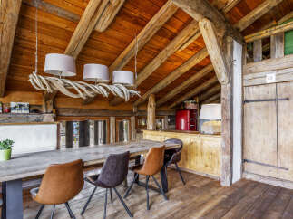 Experience rustic charm in this dining area featuring a large wooden table surrounded by stylish chairs.