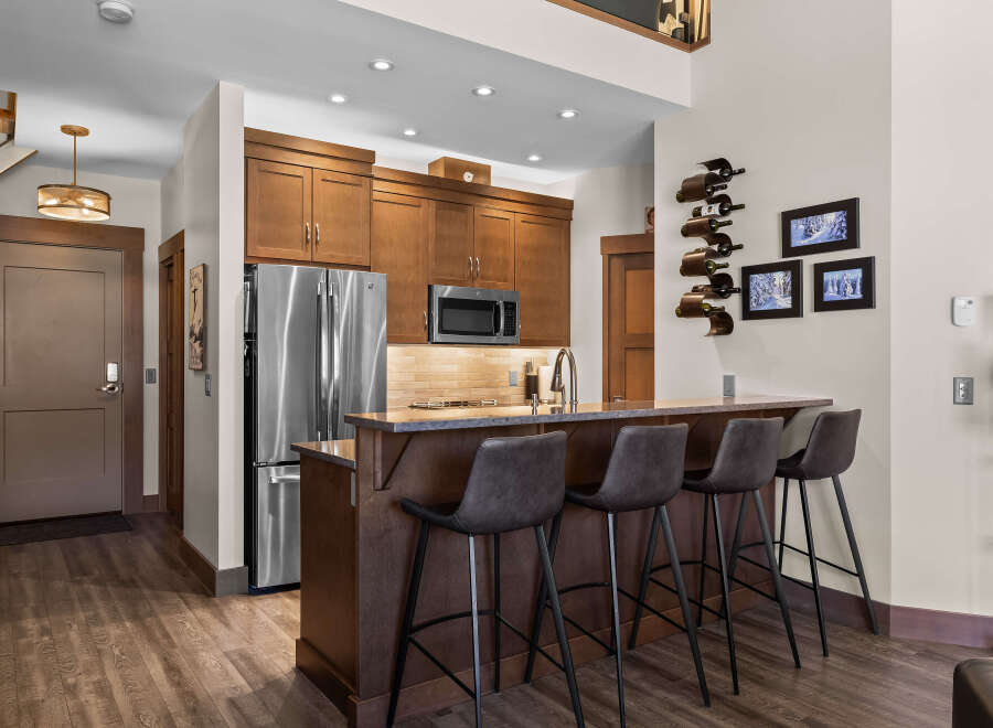 This modern kitchen features rich wood cabinetry, stainless steel appliances, and a sleek granite-topped island with bar seating.
