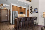 This modern kitchen features rich wood cabinetry, stainless steel appliances, and a sleek granite-topped island with bar seating.