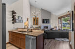 Experience luxury mountain living in this stunning property featuring a modern kitchen with a wine rack and a spacious living area with a fireplace and large windows offering breathtaking views.