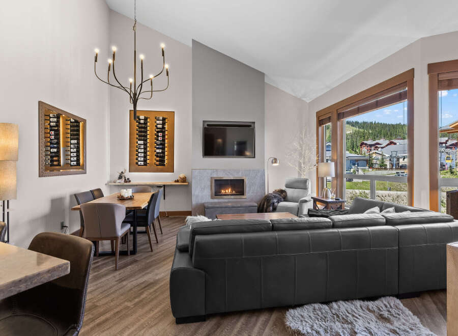 Experience luxury mountain living in this stunning condo, featuring a modern living space with a cozy fireplace and a spacious sectional sofa perfect for gatherings.