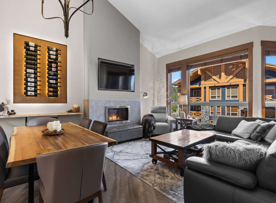 Experience luxury living in this stunning mountain retreat, featuring a spacious living area with a modern fireplace and a large window showcasing breathtaking views.