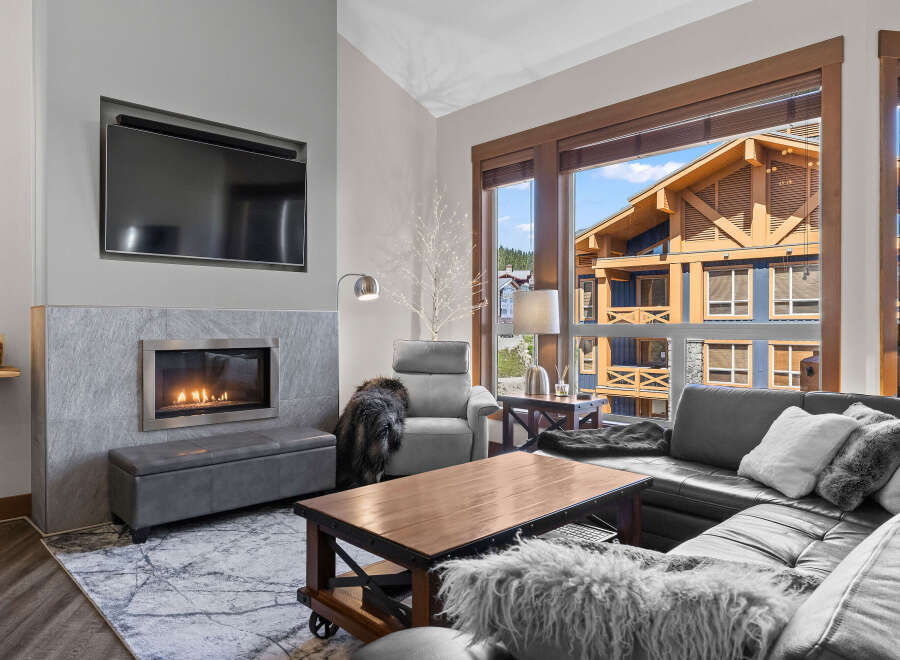 Experience modern mountain living in this stunning living room featuring a sleek gas fireplace and a large sectional sofa perfect for cozy evenings.