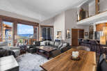Experience luxurious mountain living in this stunning open-concept living space, featuring a large sectional sofa and a rustic wooden dining table perfect for gatherings.