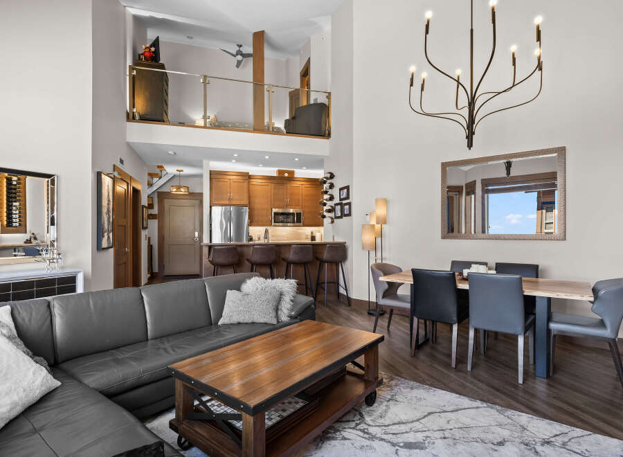 Experience modern living in this stunning open-concept loft featuring a spacious living area with a sleek leather sectional and a rustic coffee table.