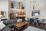 Experience modern living in this stunning open-concept loft featuring a spacious living area with a sleek leather sectional and a rustic coffee table.