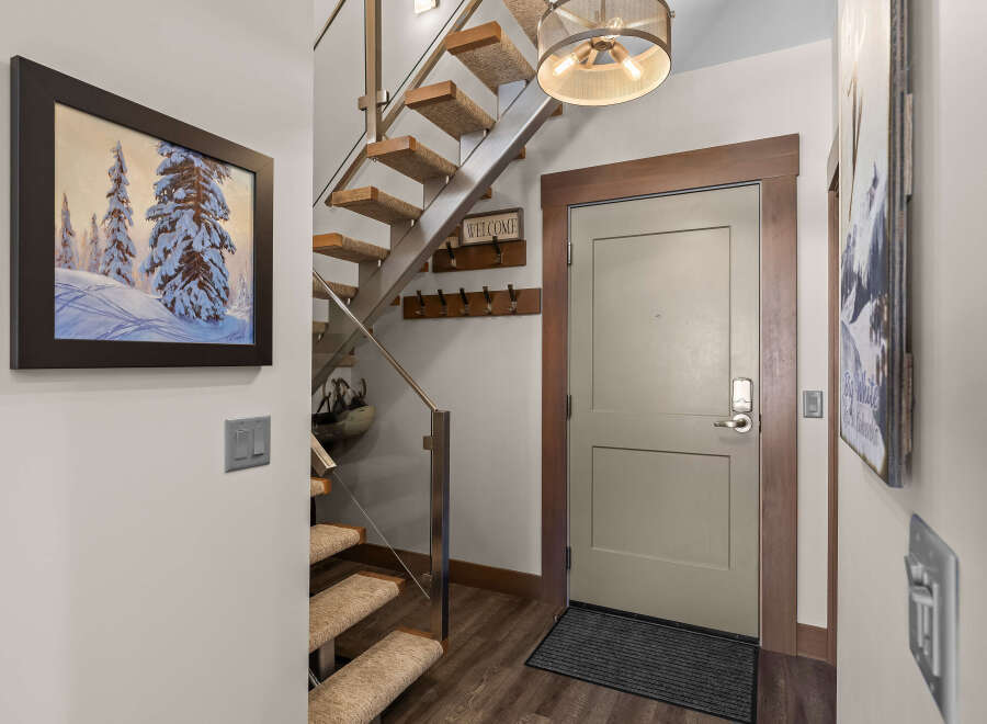 Step into this inviting entryway featuring a modern floating staircase with carpeted treads and a sleek metal railing.