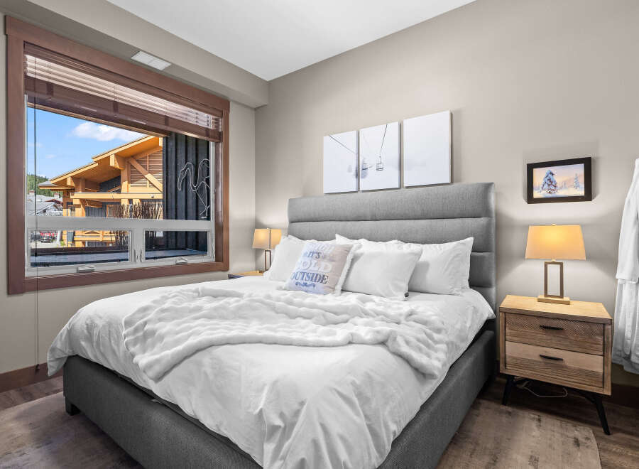 Experience ultimate comfort in this beautifully appointed bedroom, featuring a plush king-sized bed adorned with crisp white linens and a cozy faux fur throw.