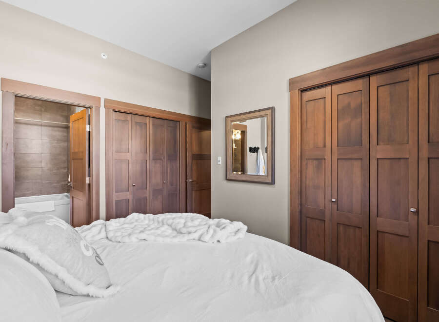 Step into this inviting bedroom featuring a plush white bed adorned with a cozy throw and decorative pillows.