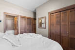 Step into this inviting bedroom featuring a plush white bed adorned with a cozy throw and decorative pillows.
