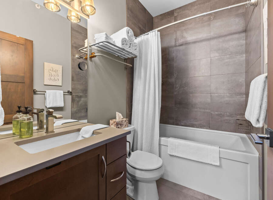 This modern bathroom features a sleek vanity with a vessel sink and brushed nickel fixtures, complemented by a large mirror and elegant lighting.