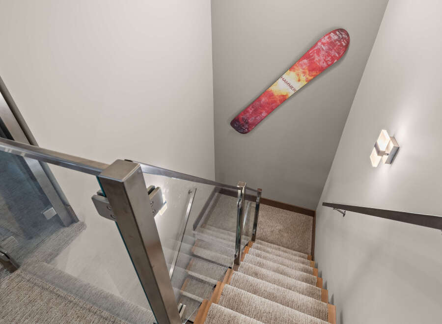 Ascend or descend in style with this modern staircase featuring sleek glass railings and plush carpeted steps.