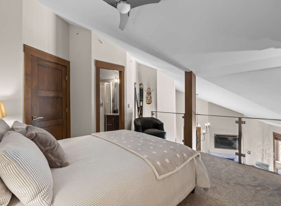 Experience luxury in this stunning loft bedroom, featuring a comfortable bed adorned with striped linens and a charming star-patterned throw.