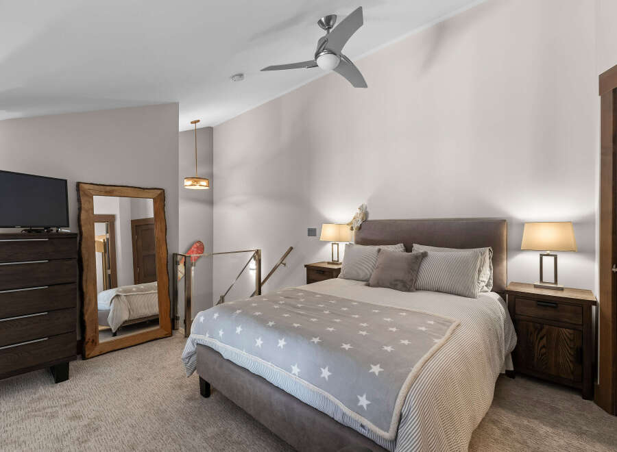 Experience ultimate comfort in this beautifully appointed bedroom, featuring a plush king-sized bed adorned with a charming star-patterned blanket.