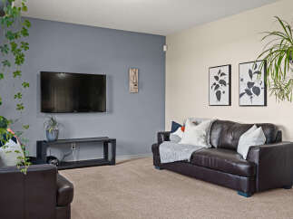 This inviting living room features a large, dark leather sofa adorned with plush throw pillows and a cozy blanket, perfect for relaxing evenings.