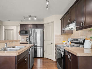 Discover this beautifully appointed kitchen featuring dark wood cabinetry, sleek stainless steel appliances including a side-by-side refrigerator and a modern range.