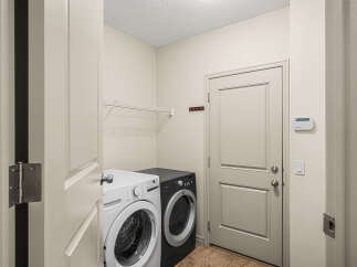 This laundry room features a white front-load washer and a black front-load dryer, perfect for handling your laundry needs.