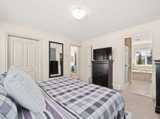 This spacious master bedroom features a comfortable king-sized bed with a stylish plaid comforter, perfect for relaxation.