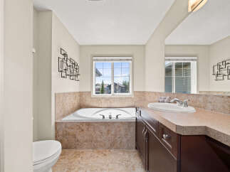 Indulge in relaxation in this spacious bathroom, featuring a luxurious corner jetted tub perfect for unwinding.