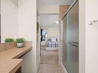 This spacious master suite offers a seamless transition from a well-appointed bathroom to a comfortable bedroom.