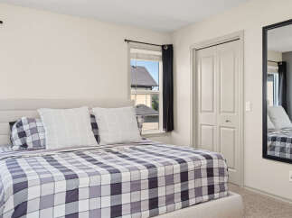 Experience comfort and style in this inviting bedroom, featuring a plush bed with a striking plaid comforter and matching pillows.