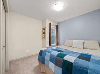 Discover comfort and style in this inviting bedroom, featuring a cozy bed adorned with a unique patchwork quilt.