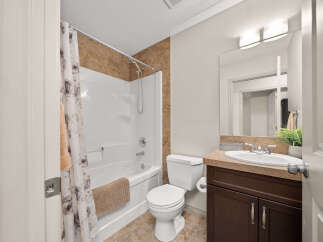 This bright and clean bathroom features a white bathtub with a floral shower curtain and a textured tile accent wall.
