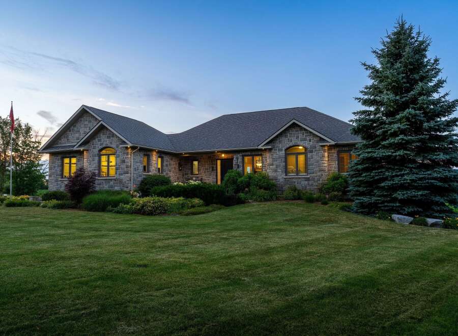 Experience luxury living in this stunning stone-clad residence, perfectly situated at dusk.