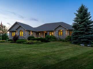 Experience luxury living in this stunning stone-clad residence, perfectly situated at dusk.