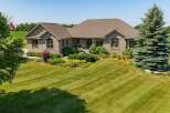 Discover this stunning stone-clad residence, featuring a beautifully landscaped yard with vibrant greenery and mature trees.