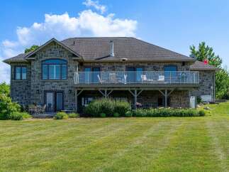 This stunning stone-clad home features a spacious walk-out basement and an expansive upper-level deck with glass railings, perfect for entertaining.