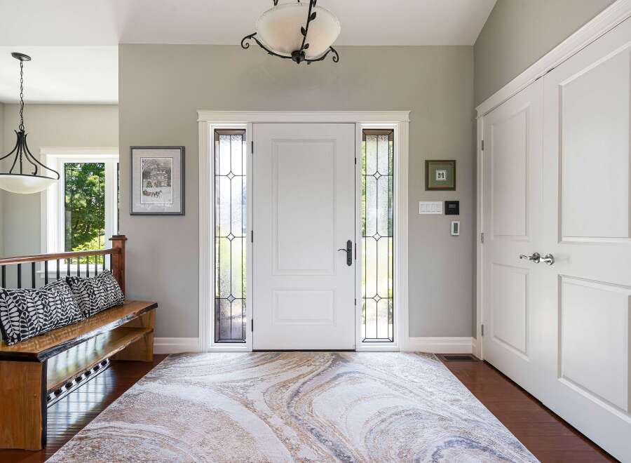 Step into a welcoming foyer featuring a grand white double door entrance with elegant stained-glass sidelights.