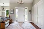 Step into a welcoming foyer featuring a grand white double door entrance with elegant stained-glass sidelights.