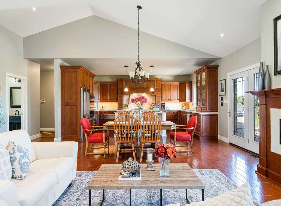 Experience the epitome of open-concept living in this stunning home, featuring a spacious kitchen with rich wood cabinetry and a large island, seamlessly flowing into a bright dining area perfect for gatherings.