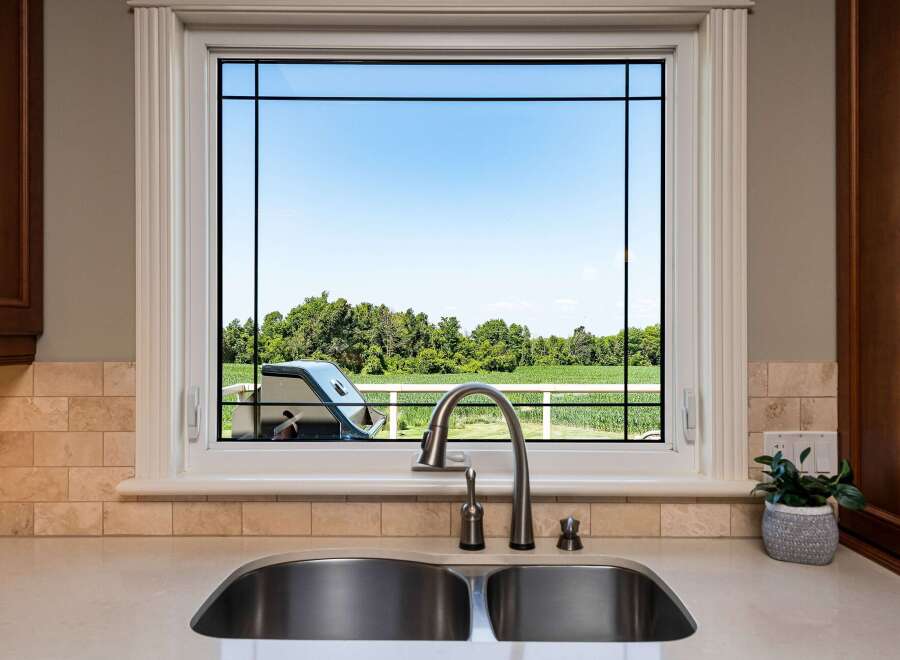 Enjoy picturesque views from this kitchen window, overlooking a lush green landscape and a clear blue sky.