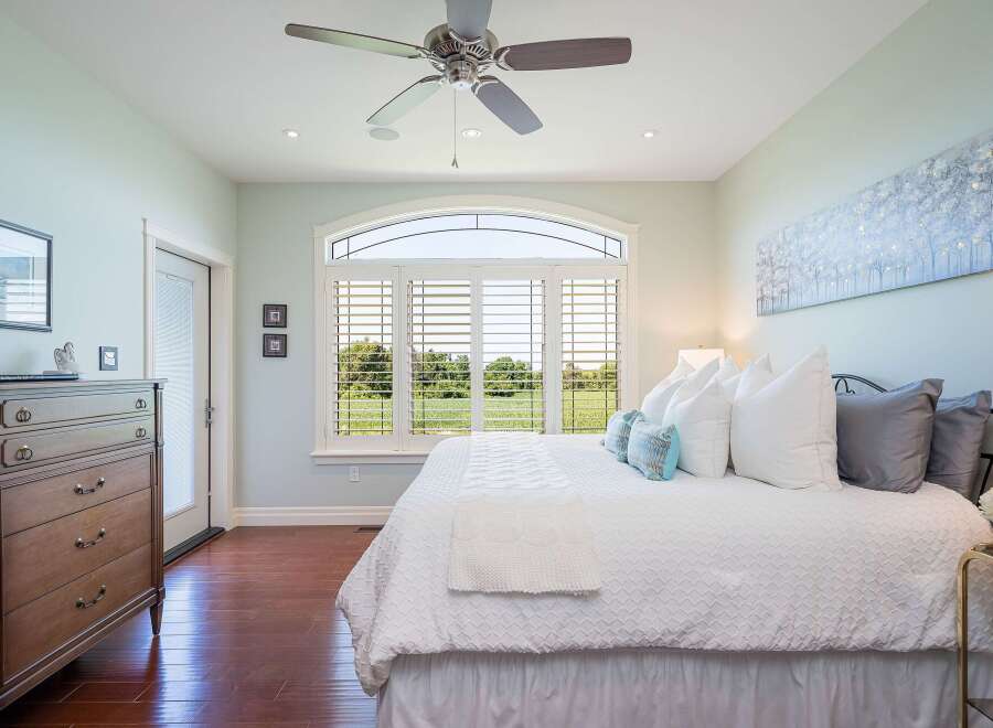 Experience luxury living in this stunning bedroom featuring a spacious king-sized bed adorned with plush pillows and a textured white duvet.
