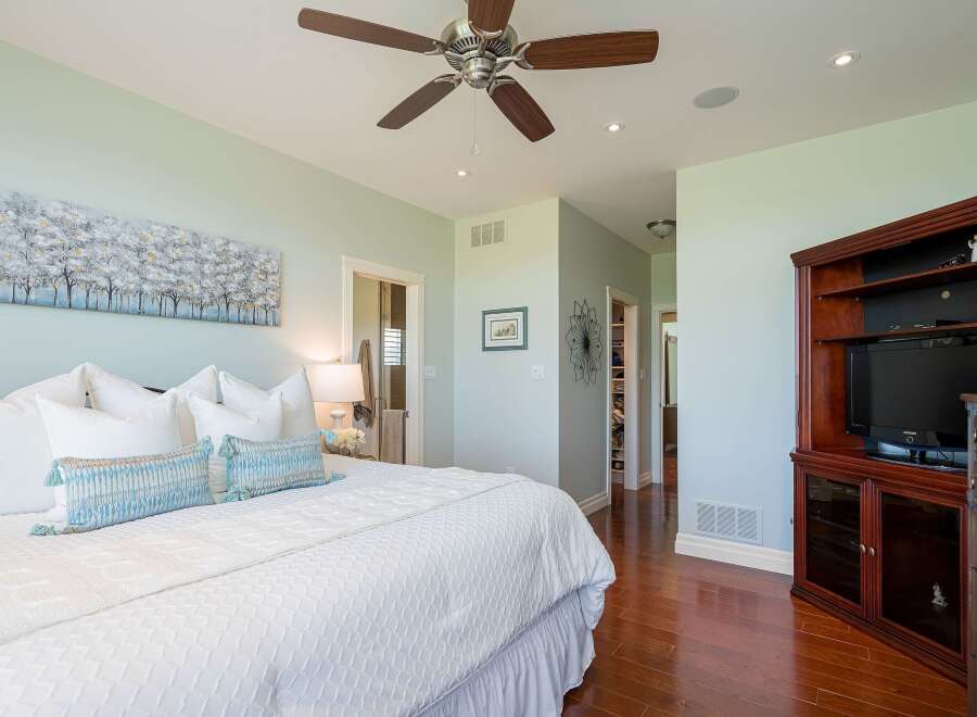 Experience luxury in this master suite, featuring a king-sized bed adorned with plush pillows and a textured white duvet.