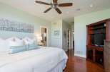 Experience luxury in this master suite, featuring a king-sized bed adorned with plush pillows and a textured white duvet.