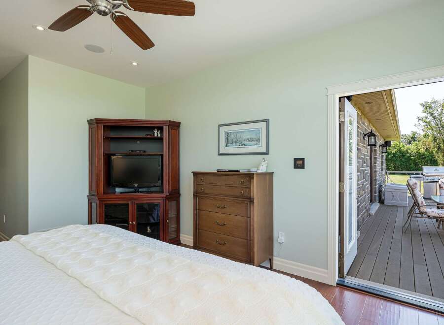This master bedroom offers a serene retreat with a cozy ambiance, featuring a large bed with a plush white comforter and a ceiling fan for comfort.