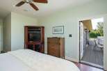 This master bedroom offers a serene retreat with a cozy ambiance, featuring a large bed with a plush white comforter and a ceiling fan for comfort.