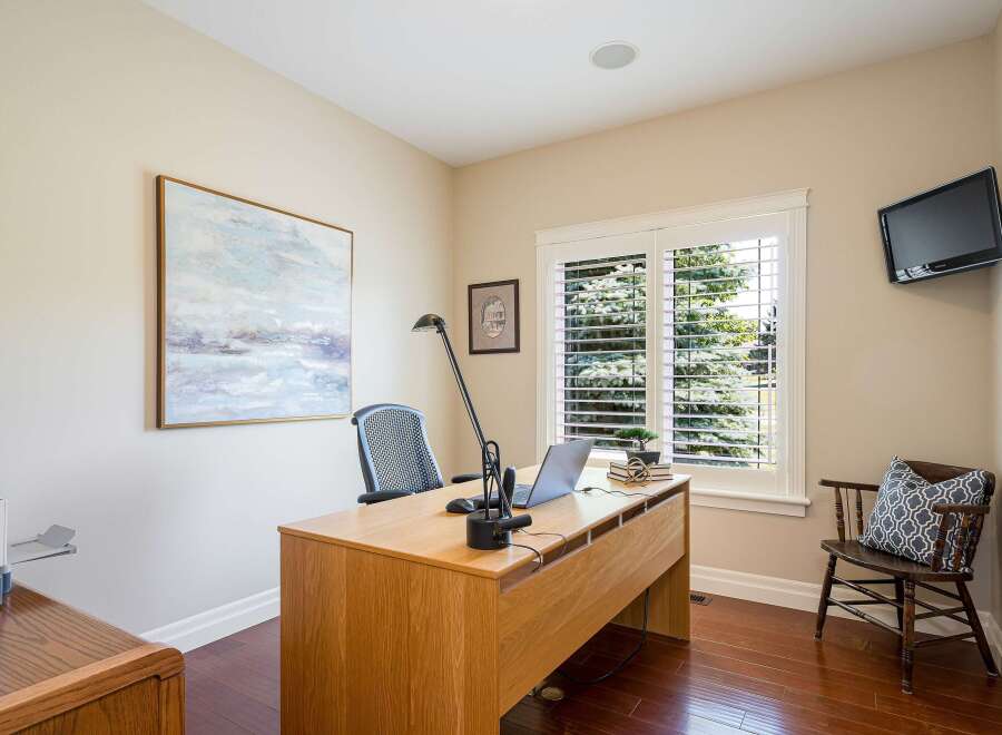 This home office features a spacious wooden desk equipped with a laptop and a modern desk lamp, perfect for productivity.