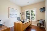 This home office features a spacious wooden desk equipped with a laptop and a modern desk lamp, perfect for productivity.