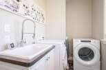 This laundry room features a spacious utility sink with a high-arc faucet, perfect for pre-treating clothes or hand-washing delicate items.